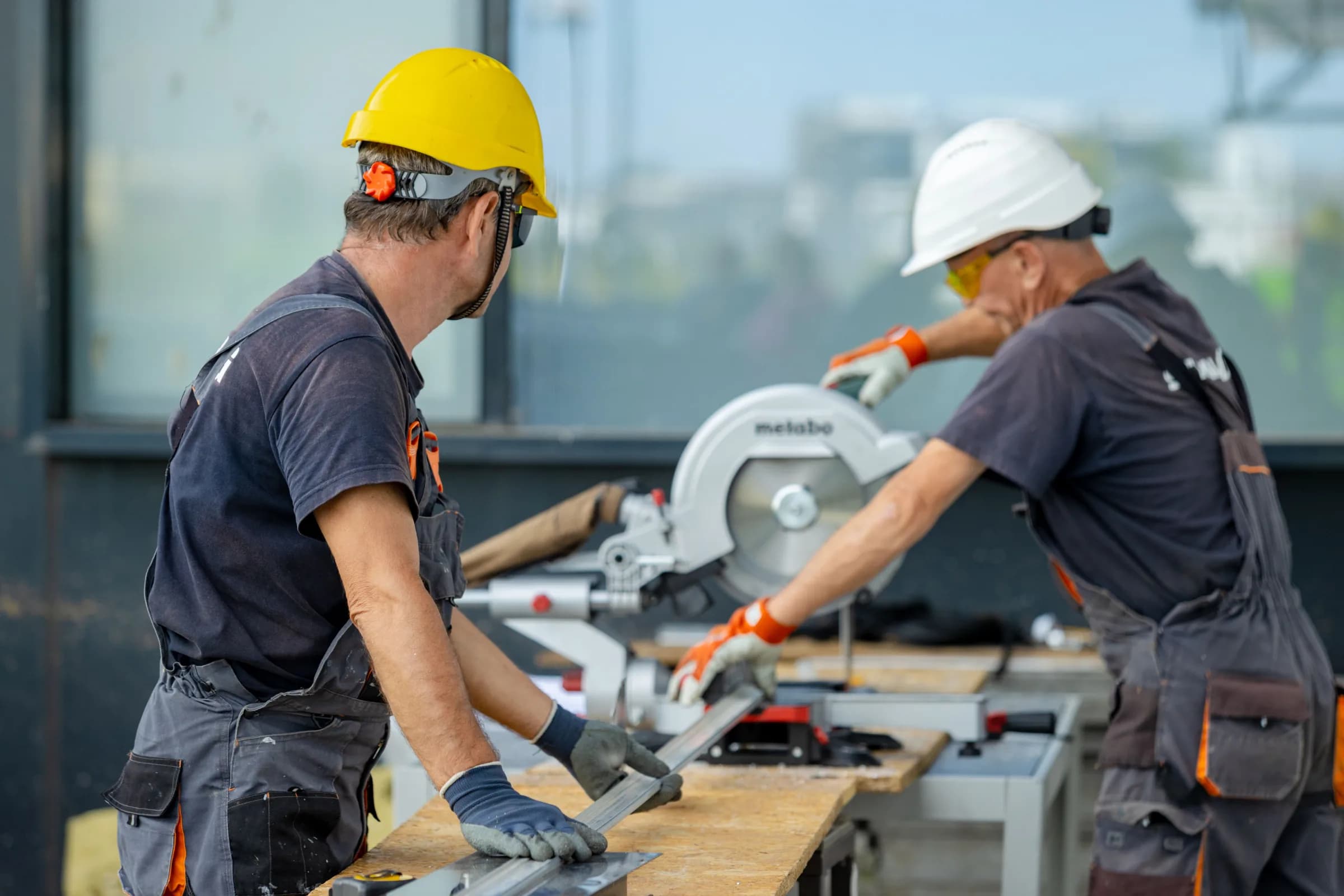 Workers wearing protective gloves while cutting metal